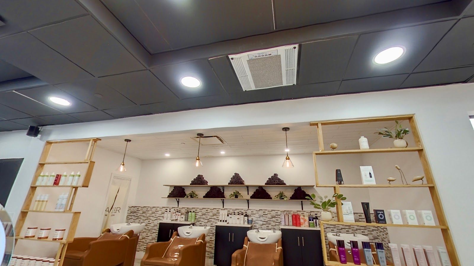 The shampoo area at Haiier Hair Salon: wash basins with tan chairs beneath wooden shelves of hair products